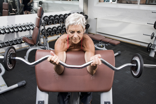 Elderly woman lifting weights at fitness center