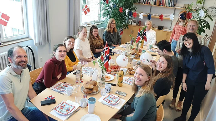 Mennesker som sitter rundt et pyntet frokostbord med norske flagg