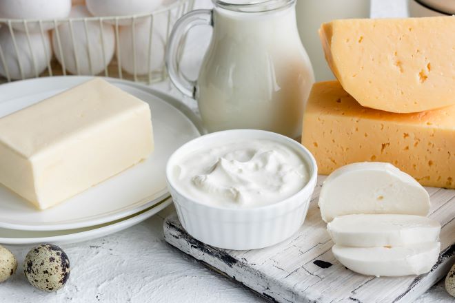 Foto av frokostbord med en mugge melk, noen oster, en bit smør og en skål med rømme.