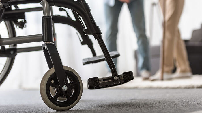 wheelchair in focus and person with walking stick in the background