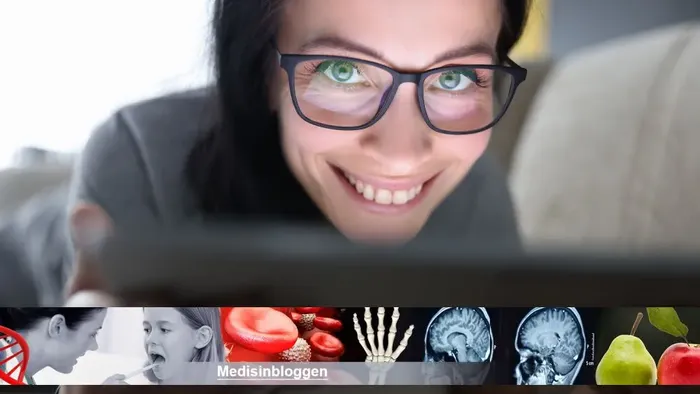 Smilende kvinne som titter over kanten på en bærbar PC.