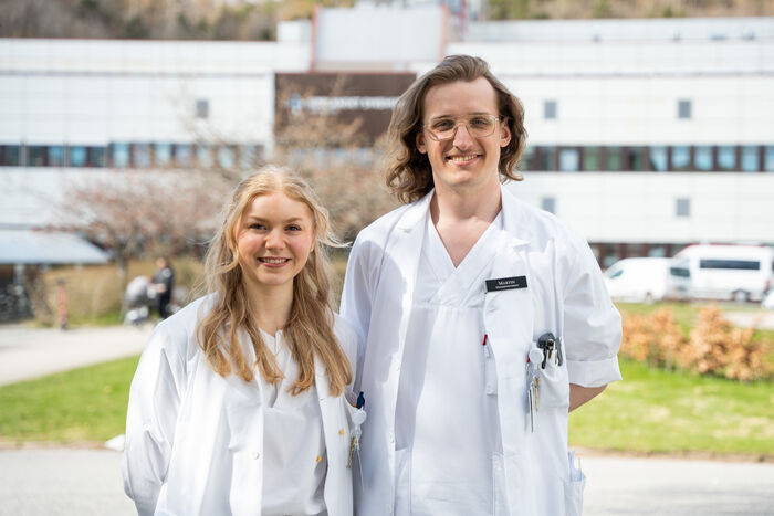 To studenter som smiler foran sykehuset.