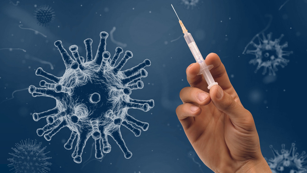A vaccine particle and a hand holding a syringe